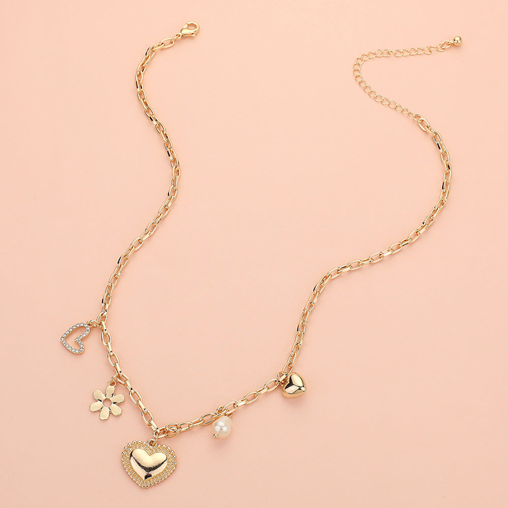 Introducing Love Blossoms - Gold Charm Necklace: a stunning piece with a crystal-studded heart, daisy flower, pearl bead, and golden heart, all showcased on a soft pale pink background for an elegant touch.