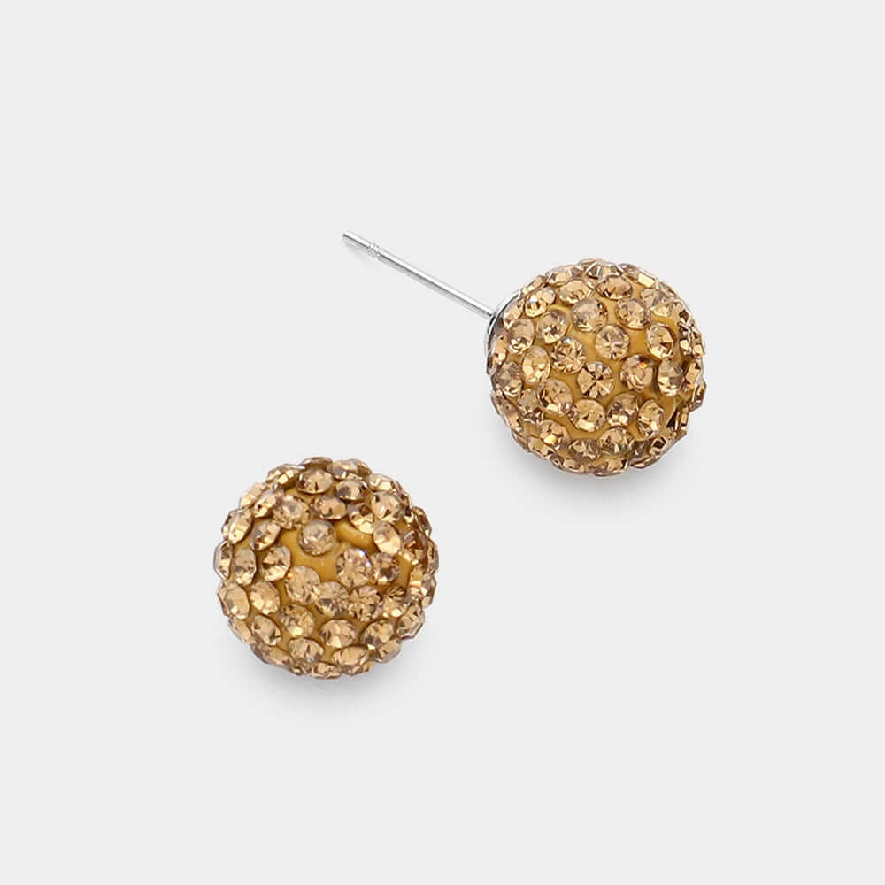 A pair of Sugar Rush - Topaz Stud Earrings featuring round shapes with small, sparkling gold crystals on a white background; one earring lies flat, while the other stands upright displaying the post.