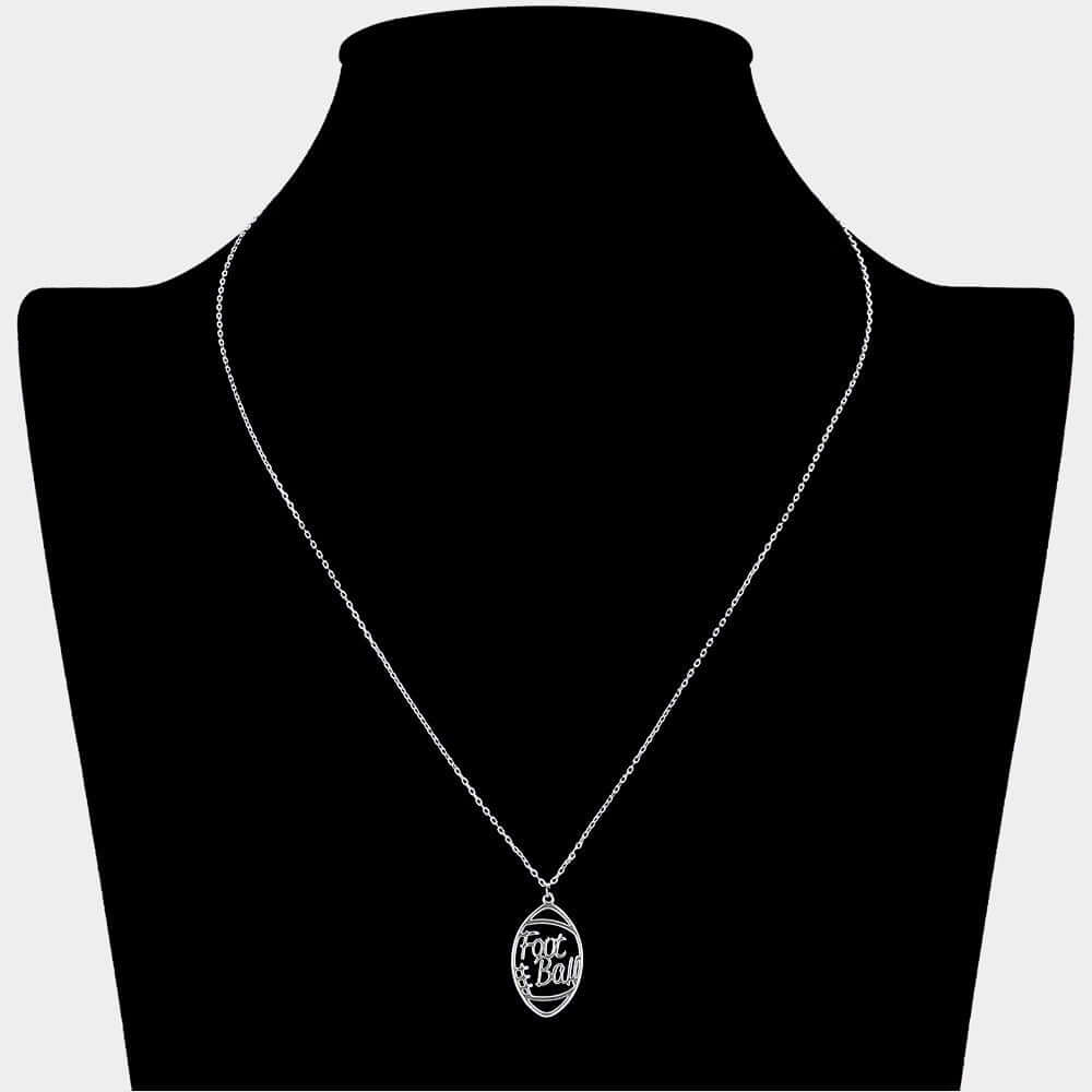 The Half Time Hype - Silver Necklace features a silver football-shaped pendant engraved with "Foot & Ball," making it perfect game day jewelry. Displayed on a black jewelry bust, it's an ideal accessory for football fans.