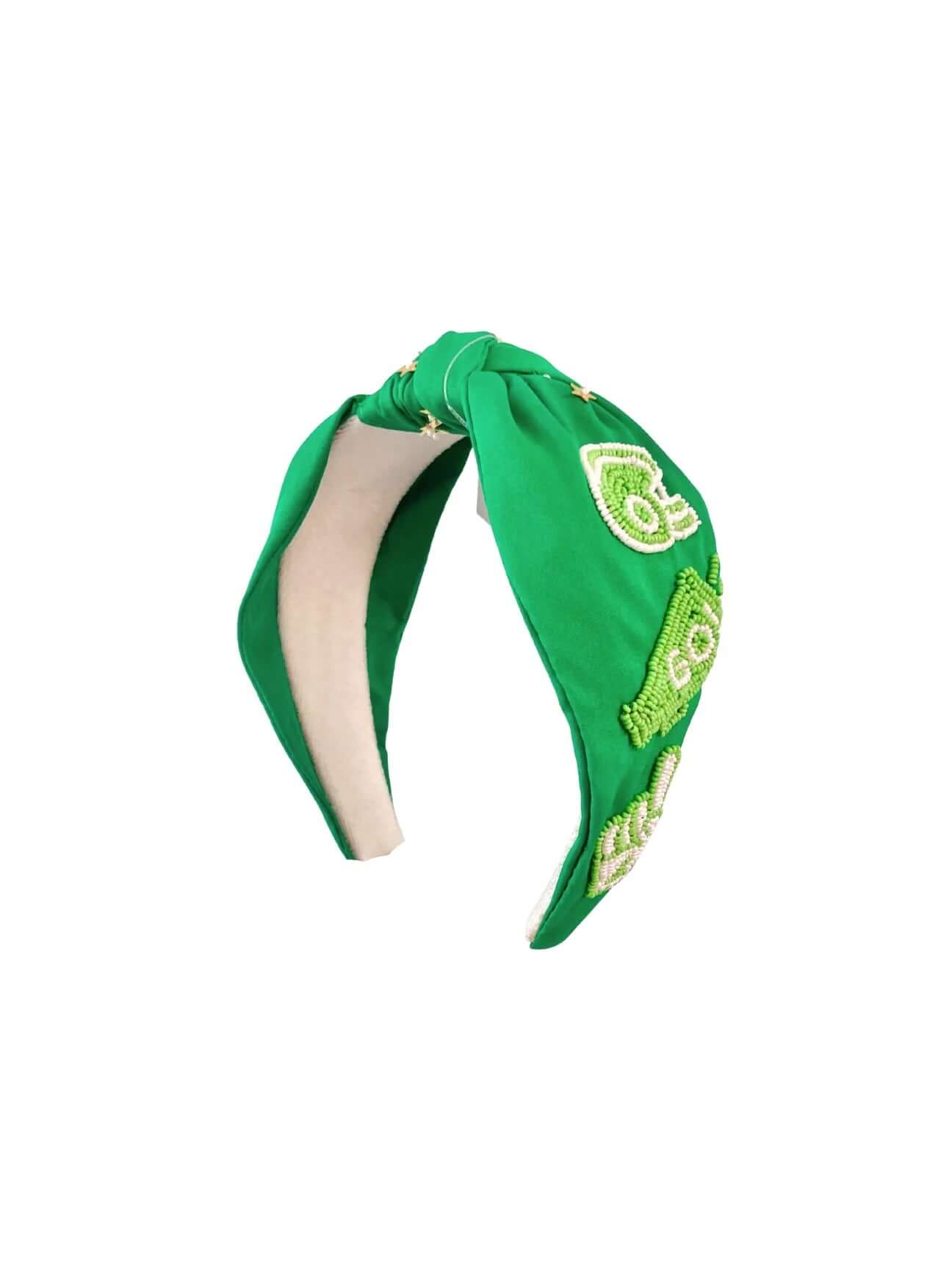 The Playbook & Pearls Green Football Headband features green and white embroidered patches in assorted shapes on a soft, light fabric—perfect for game day and showing your team spirit.