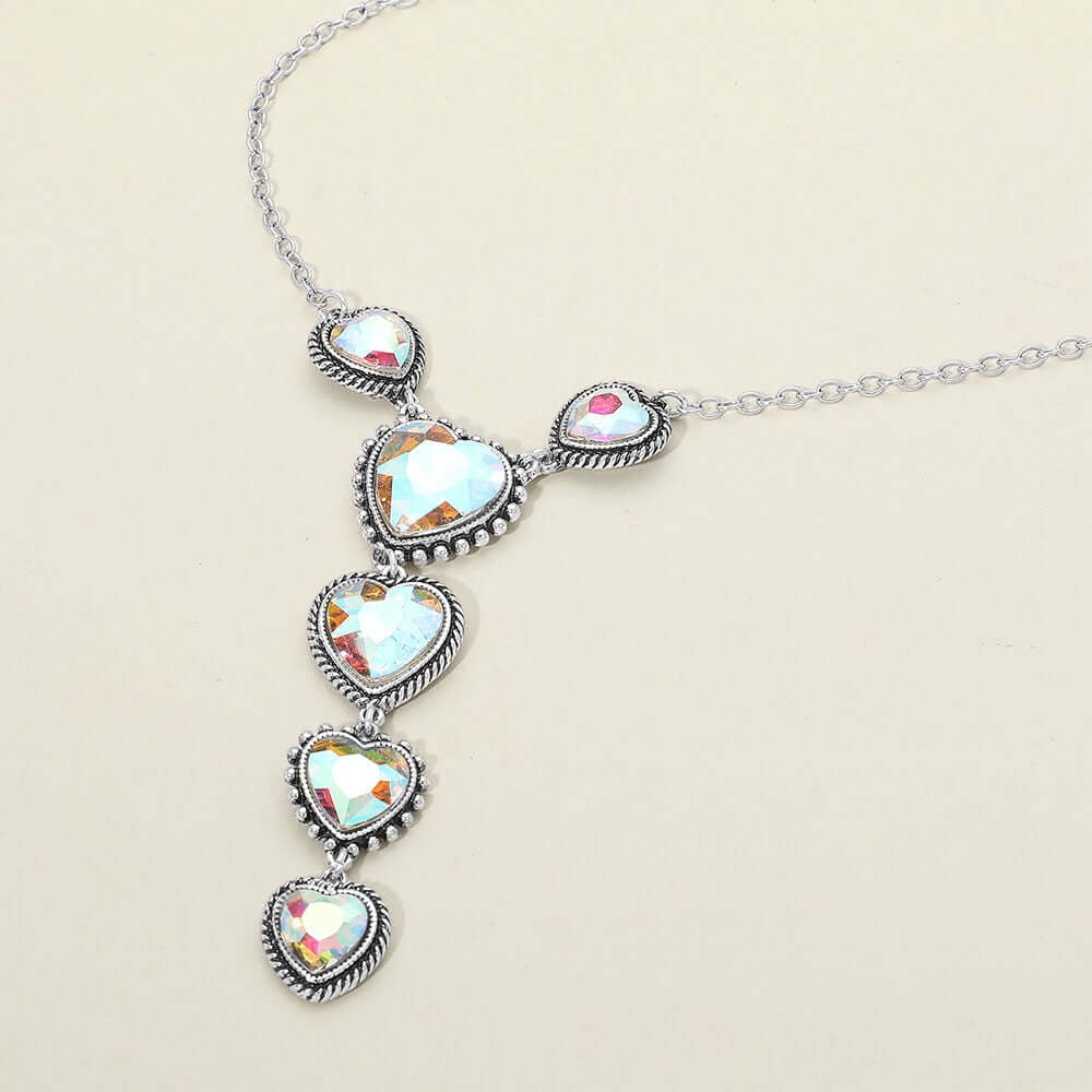 The Heartfall - Iridescent & Silver Necklace features five faceted heart pendants with graduated iridescent gems and antique-inspired silver detailing for a timeless, elegant look.