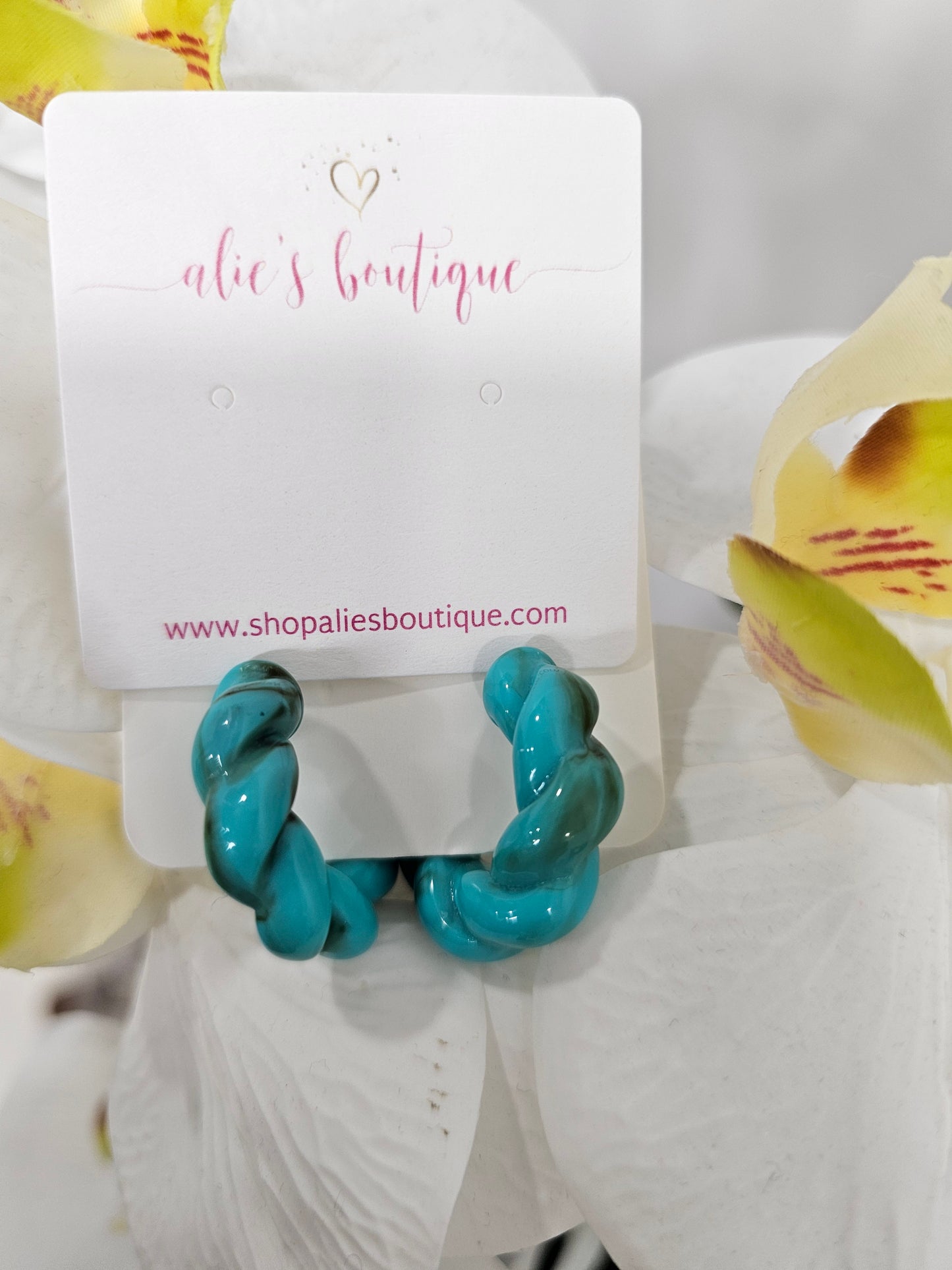 Chaotic Chic - Aqua Small Acrylic Resin Hoop Earrings, shown on a white card with “alie’s boutique” in pink script and a gold heart, are styled with white orchids featuring yellow centers for a trendy display.