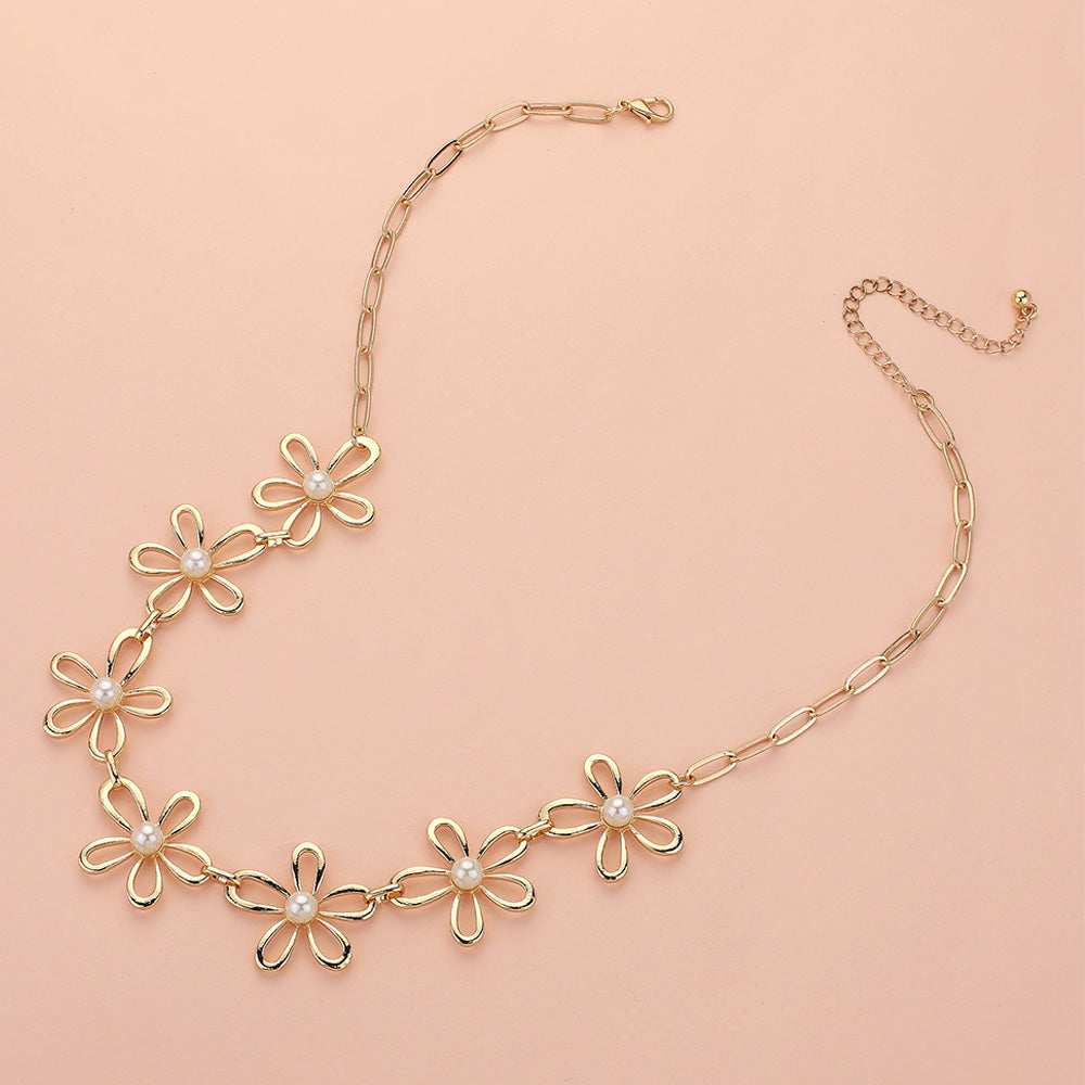 The Pure Bloom - Gold Flower Necklace features five daisy-shaped charms with white pearl centers on a chain-link design, adjustable for the perfect fit. Displayed on a light peach background, this elegant piece adds a graceful touch to any look.