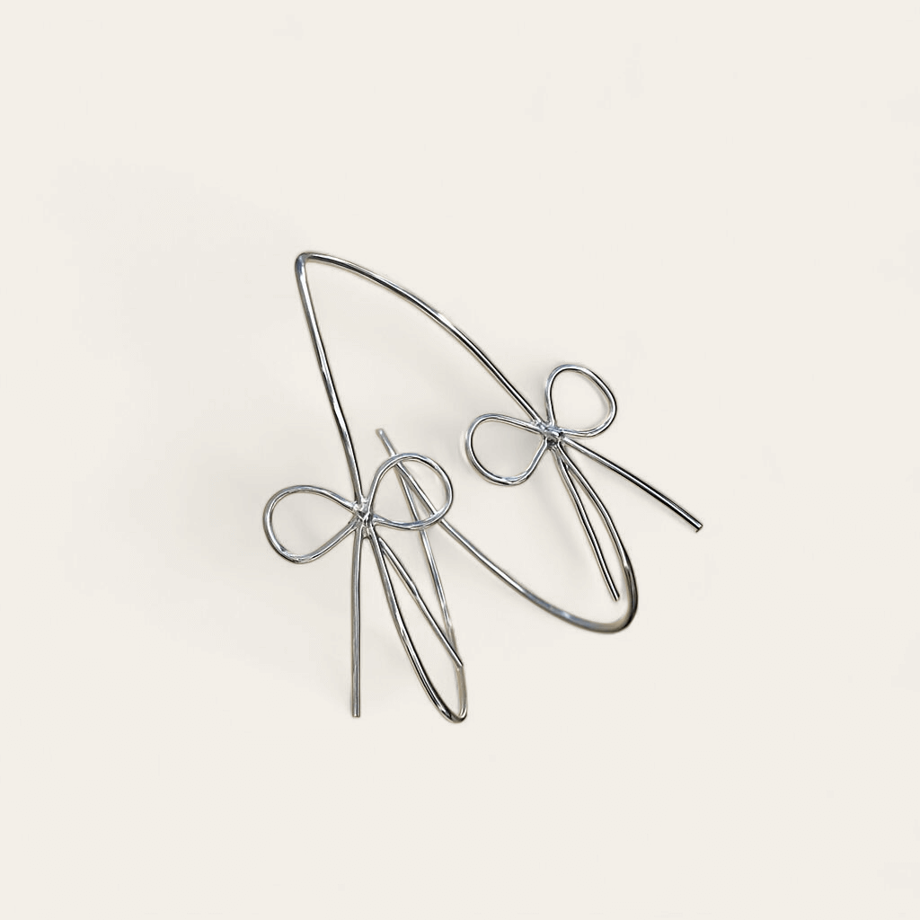 The Ladylike Bows- Silver Hoop Earrings are shown on a simple, light background, bringing an elegant touch to any feminine earring collection.