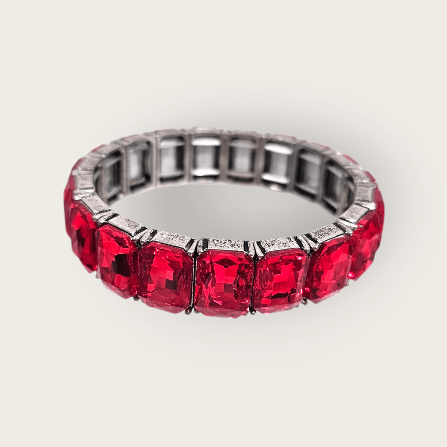 The Radiance Glow Stretch - Red Bracelet features large, cushion-cut red gemstones arranged evenly around a platinum band, crafted in the USA for an elegant look.