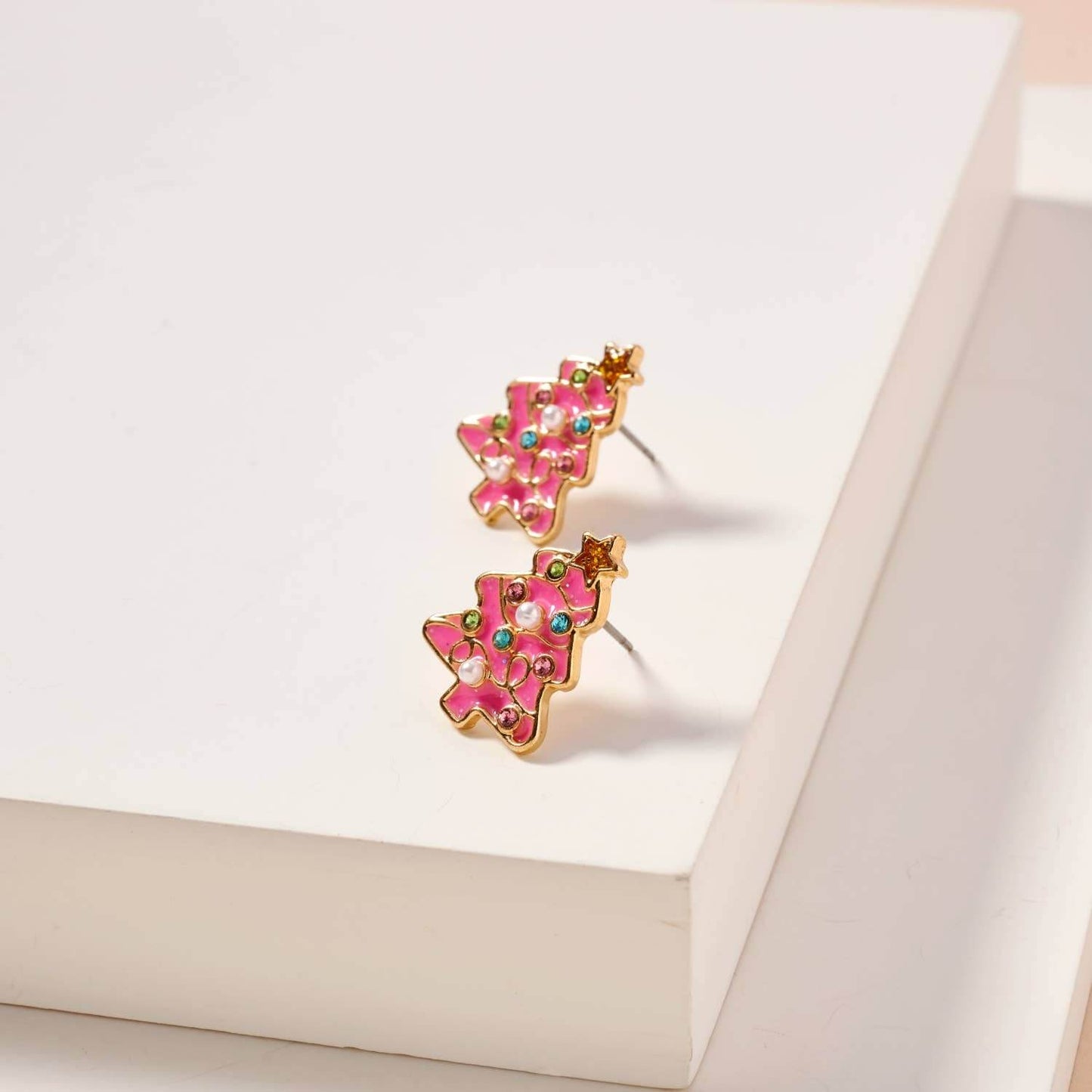 Pink and gold earrings on a white surface