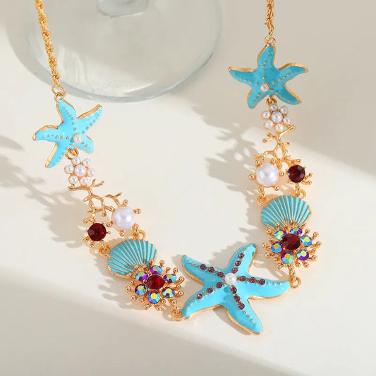 Ocean's Whisper - Blue Starfish Necklace: This ocean-inspired accessory features a gold chain with blue starfish, blue seashells, white pearls, and red gemstones. Available now in our Labor Day Sale!.