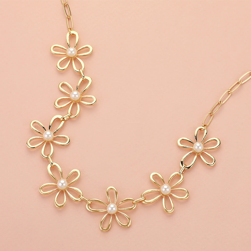 The Pure Bloom - Gold Flower Necklace features five open-petal charms accented with white pearls on an elongated oval-link chain, beautifully displayed against a light peach background.